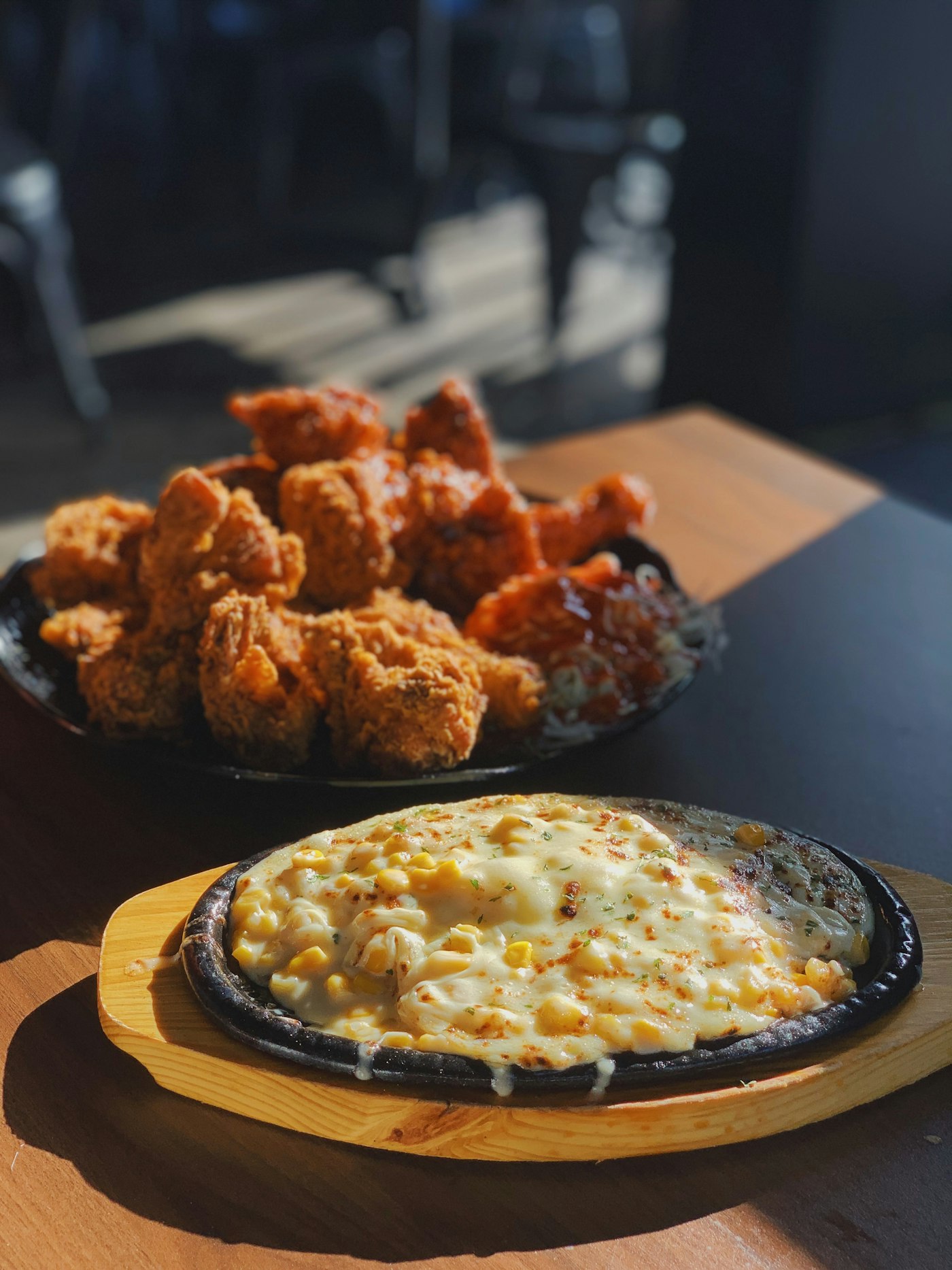 Stock photo of a Korean fried chicken platter, half crispy and half glazed, beside corn cheese on a hot plate — placeholder, not their kitchen