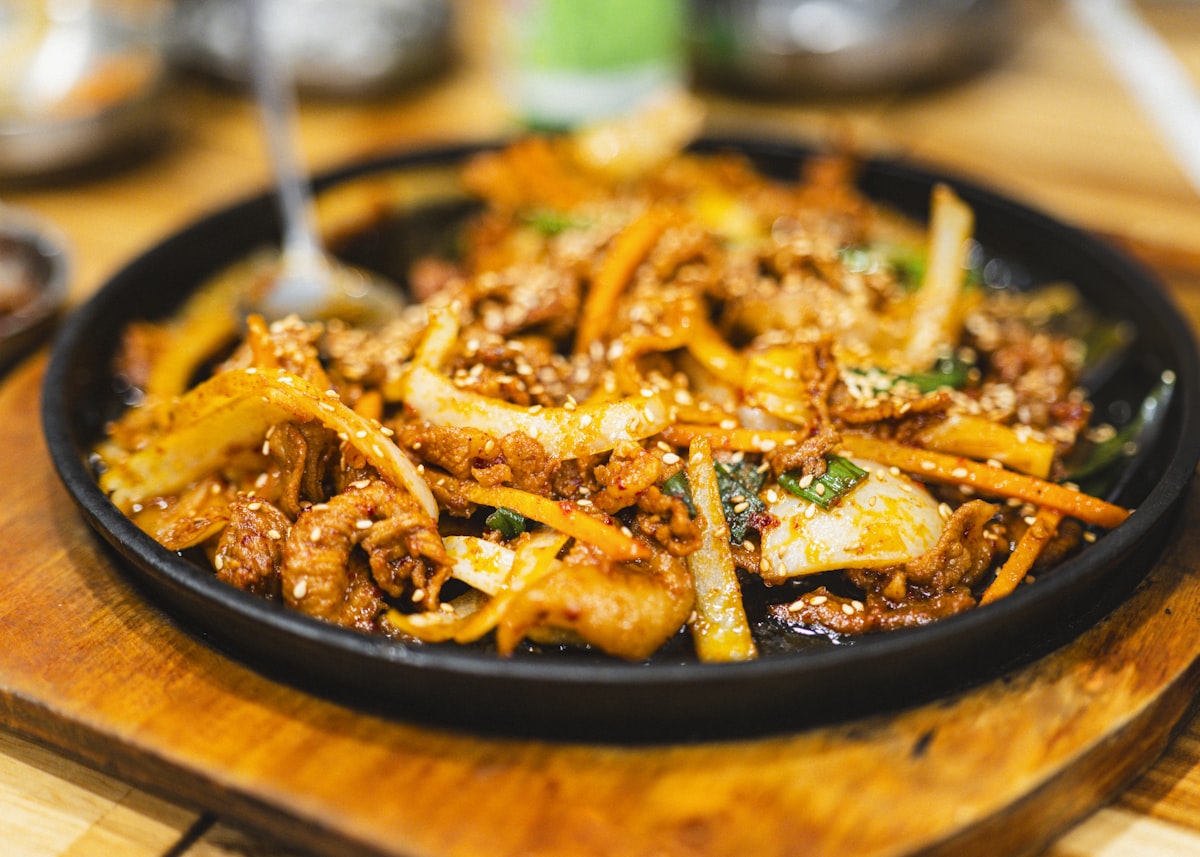 Stock photo of spicy stir-fried marinated pork on a sizzling platter — placeholder, not their kitchen
