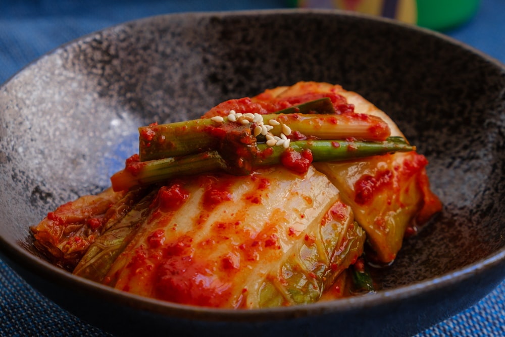 Stock photo of kimchi in a dark stoneware bowl — placeholder, not their kitchen