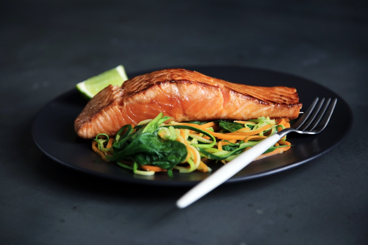 Stock photo of a grilled salmon fillet on a dark plate — placeholder, not their kitchen