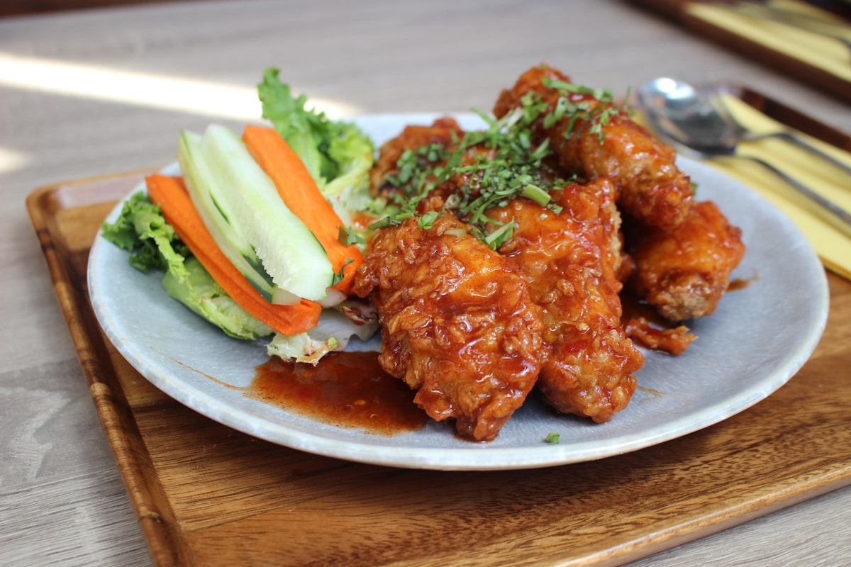 Stock photo of gochujang-glazed Korean fried chicken with fresh vegetables — placeholder, not their kitchen